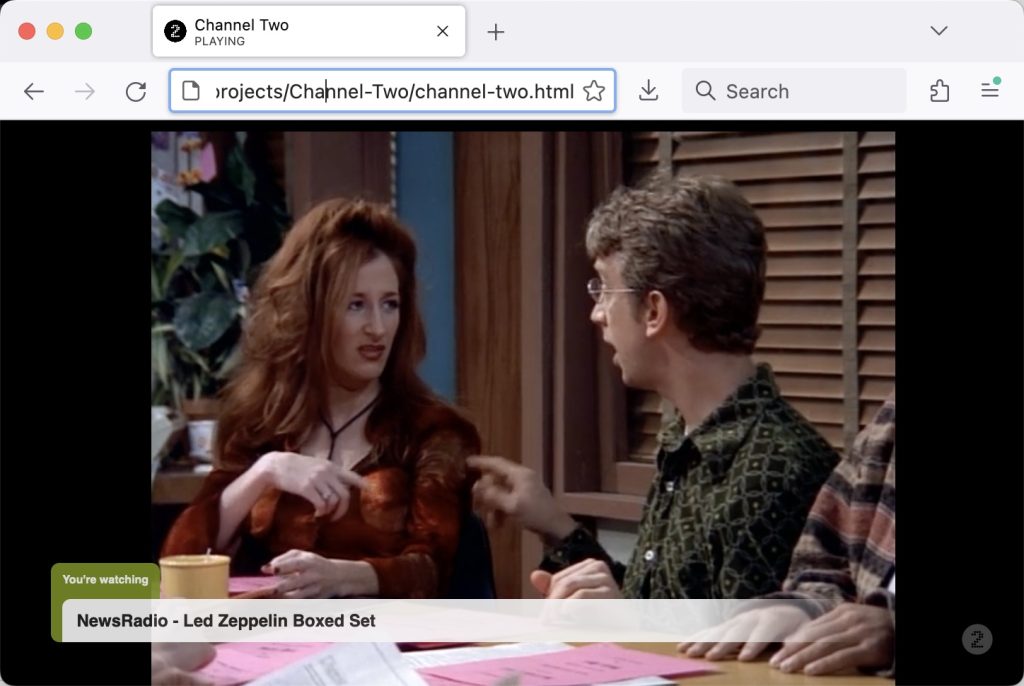 A screenshot of Channel Two broadcasting an episode of NewsRadio. It includes a chyron with the text "You're watching NewsRadio - Led Zeppelin Boxed Set." The browser chrome is visible, but Channel Two normally runs in full-screen mode.
